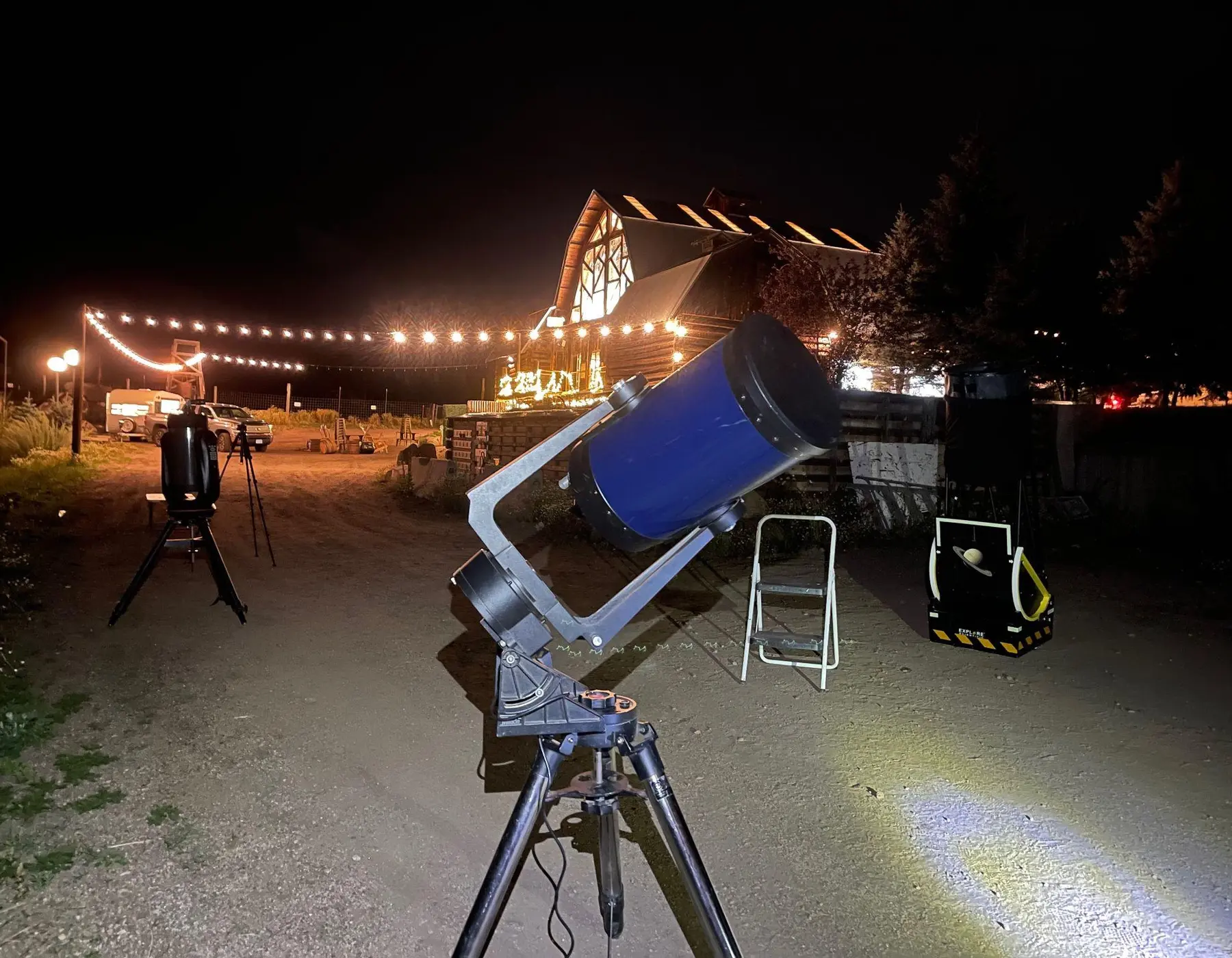 A large mobile telescope prepared outside a mountain hospitality venue at dusk